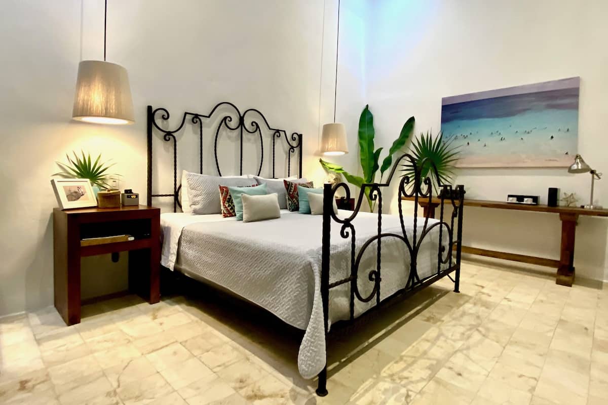 A neatly arranged bedroom with a bed, bedside tables, and a painting on the wall.