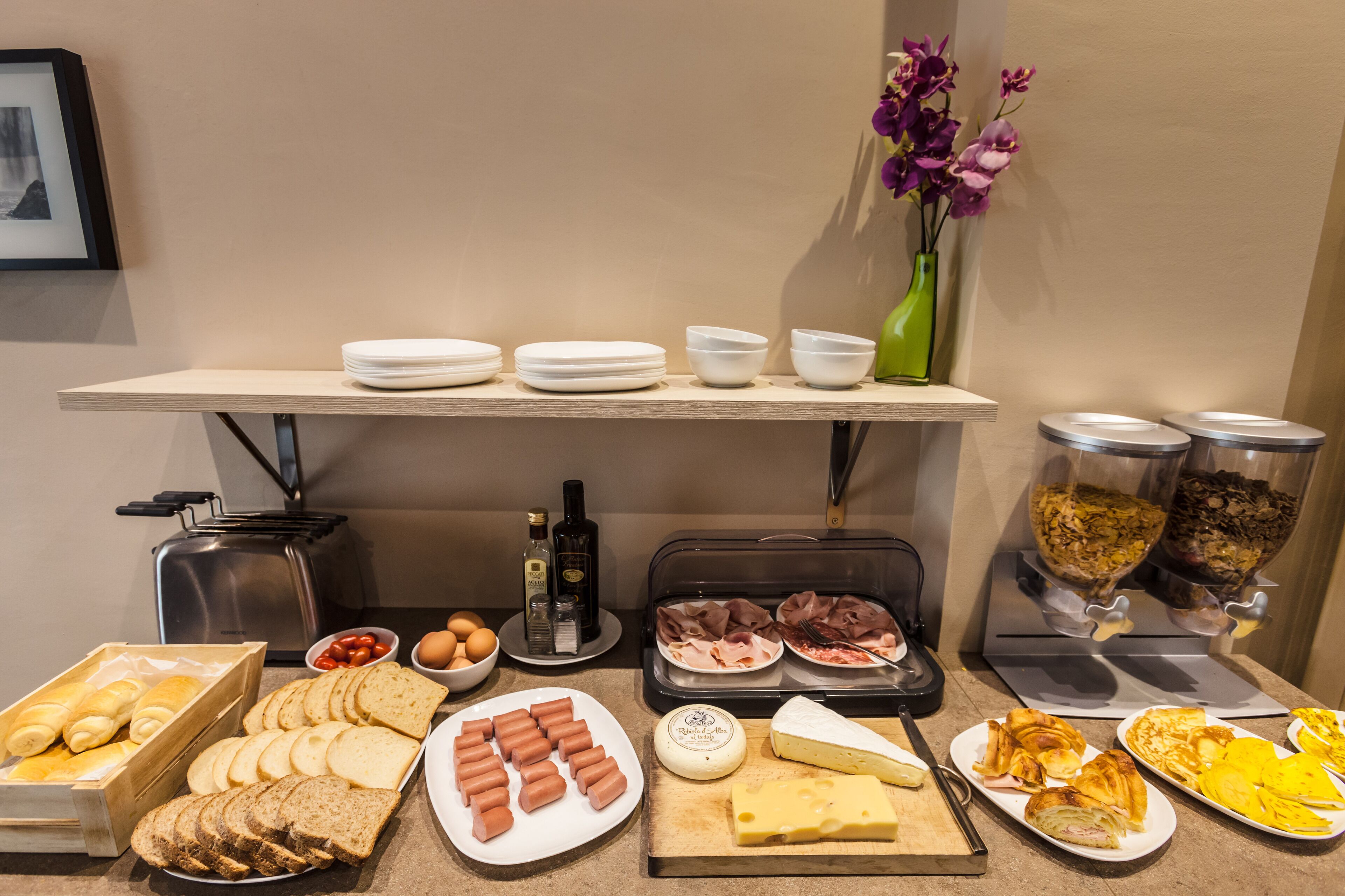 Un buffet con diverse pietanze, tra cui pane, formaggi, salumi e salse.