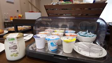 A display of various dairy products including yogurt and cheese on a buffet table.