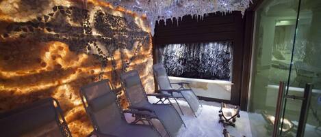 Un cuarto de spa con pared de piedra, un ventanal grande y tres sillones de descanso.