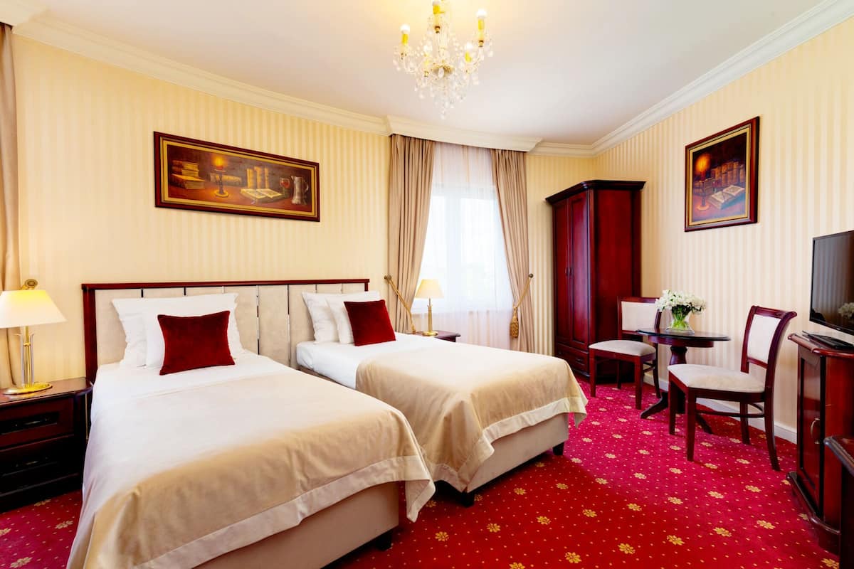 Una habitación de hotel con dos camas, televisión, escritorio y candelabro.