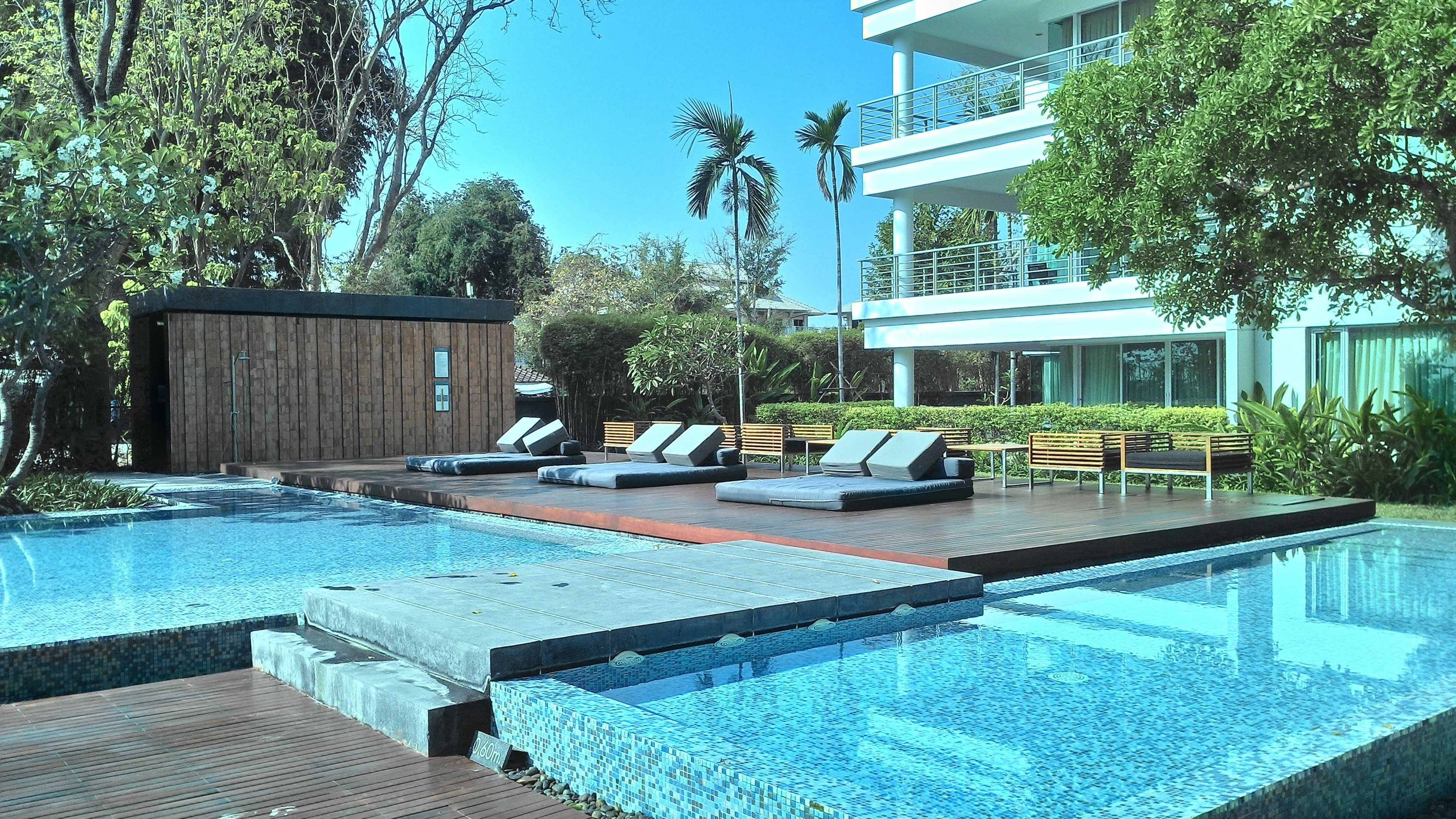 Una piscina con lettini e un solarium in legno.