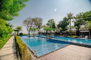 Una piscina al aire libre, sombrillas, sillones reclinables de piscina