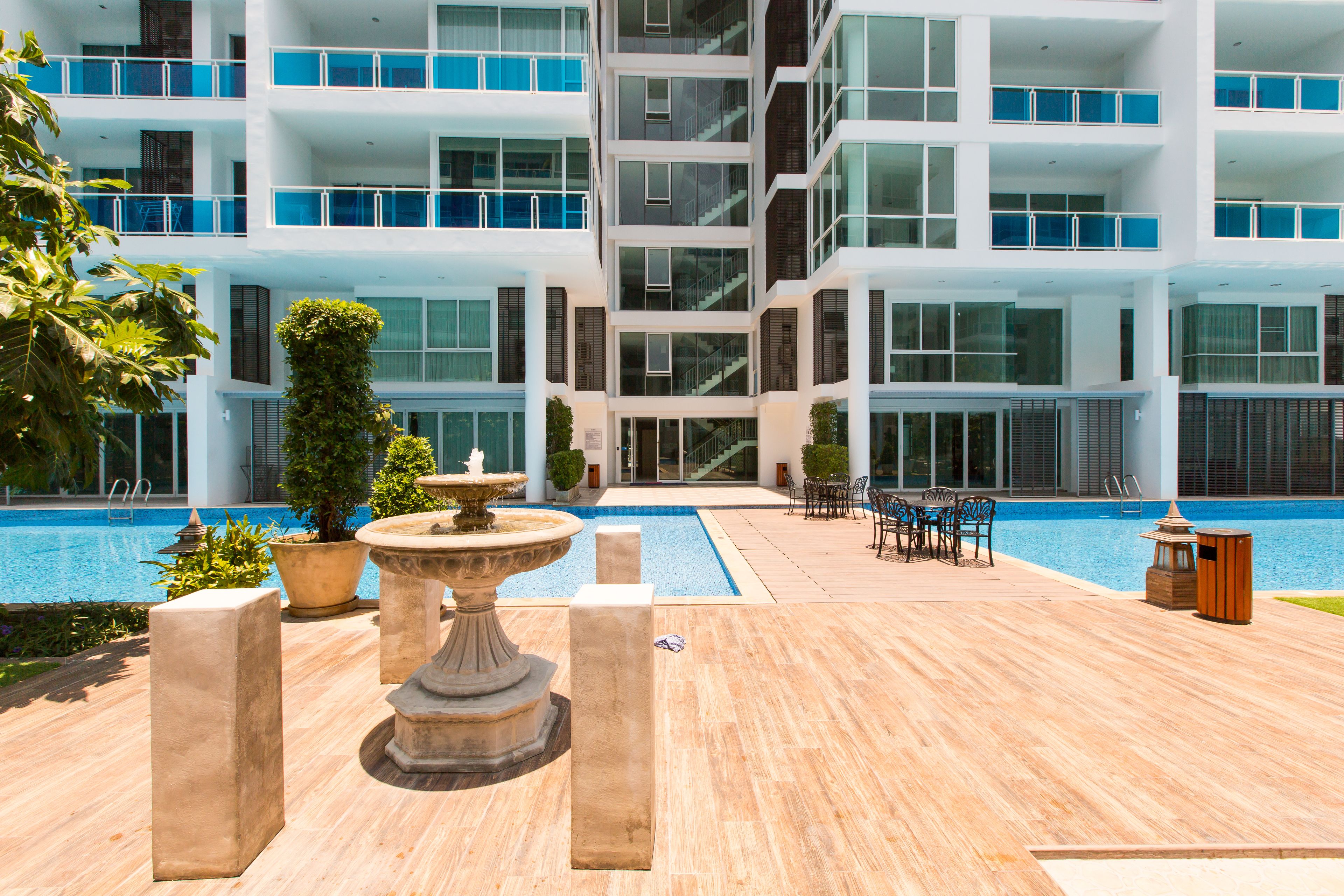 Un hôtel moderne doté d’un espace piscine comprenant une fontaine, des sièges et offrant une vue sur les différents étages du bâtiment.