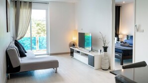 Ein modernes Wohnzimmer mit einer Couch, einem Fernseher und einem Konsolentisch mit einer Vase.