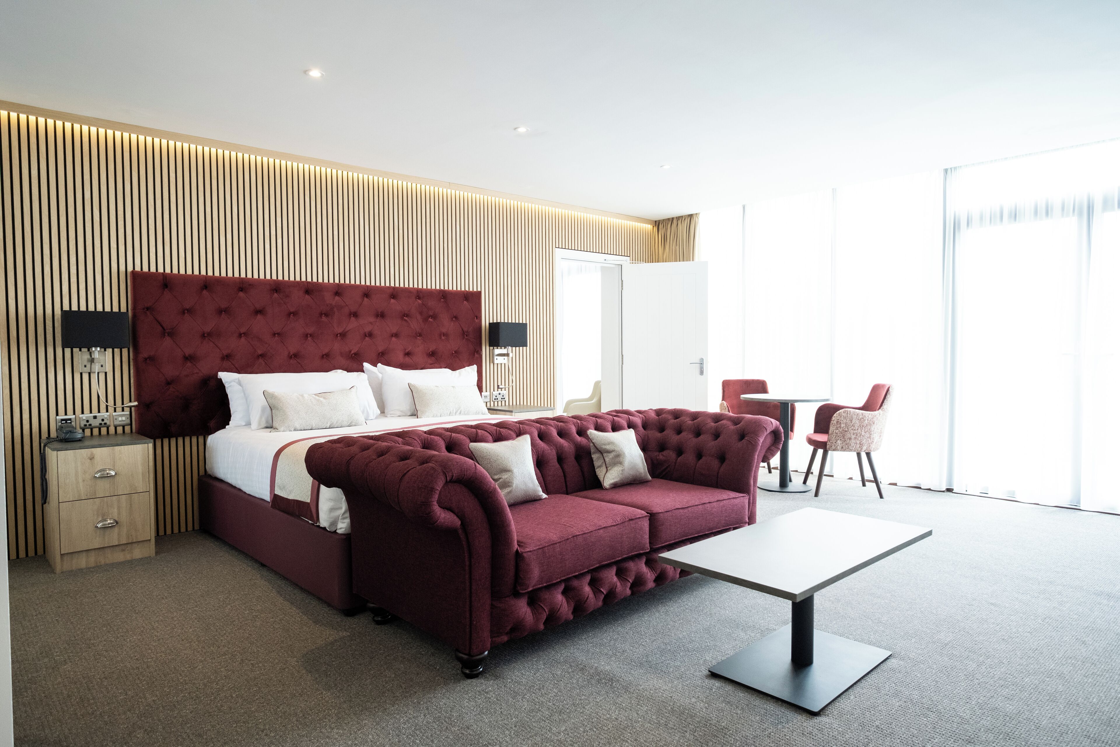 Ein modernes Hotelzimmer mit einem großen Bett, einer Couch, einem Schreibtisch und einem Sessel.
