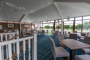 Um restaurante com chão xadrez, balaústres brancos e grandes janelas que dão para o exterior.