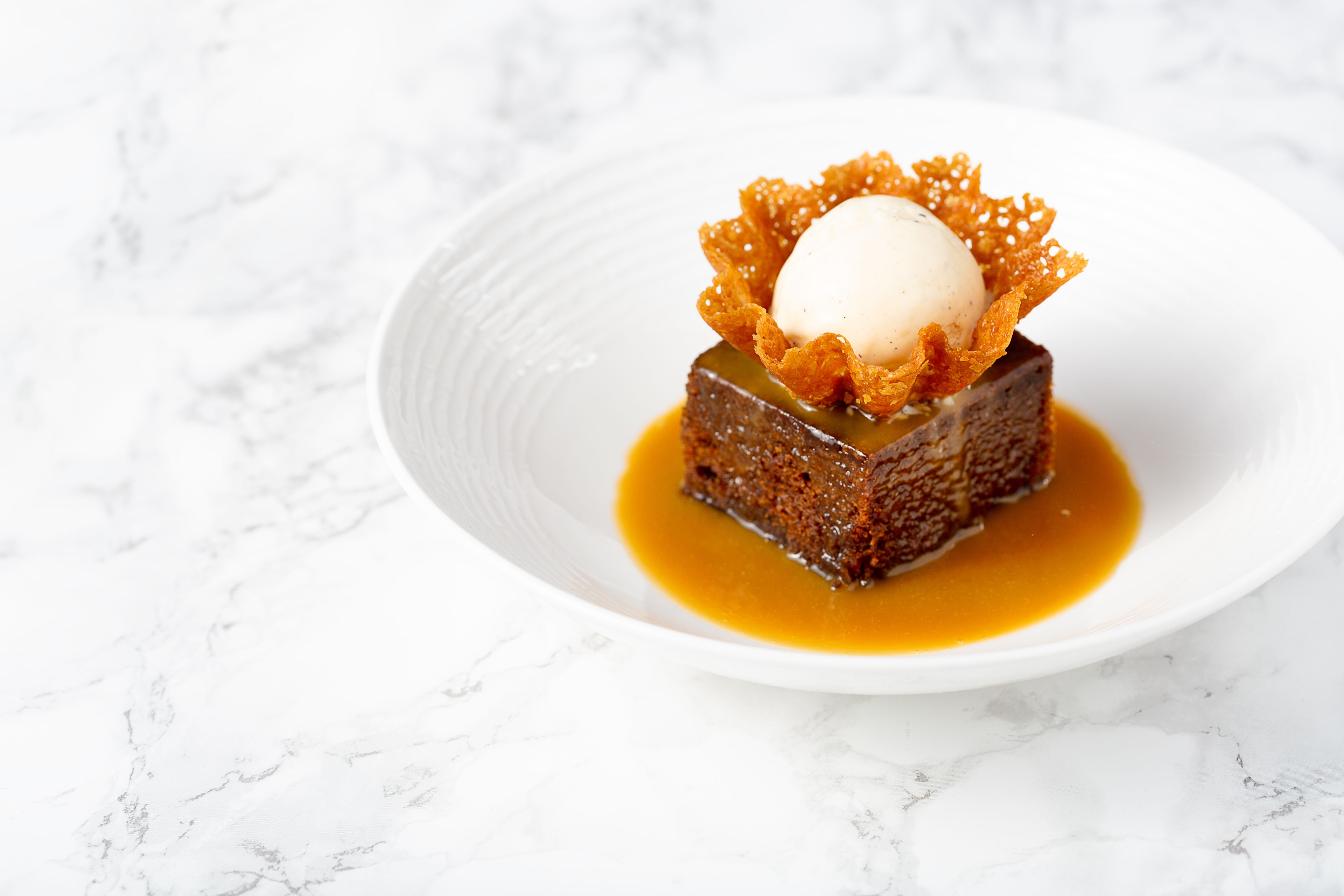 Un postre sobre un plato blanco con salsa de caramelo.