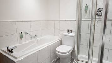 A modern bathroom with a bathtub, toilet, and glass-enclosed shower.