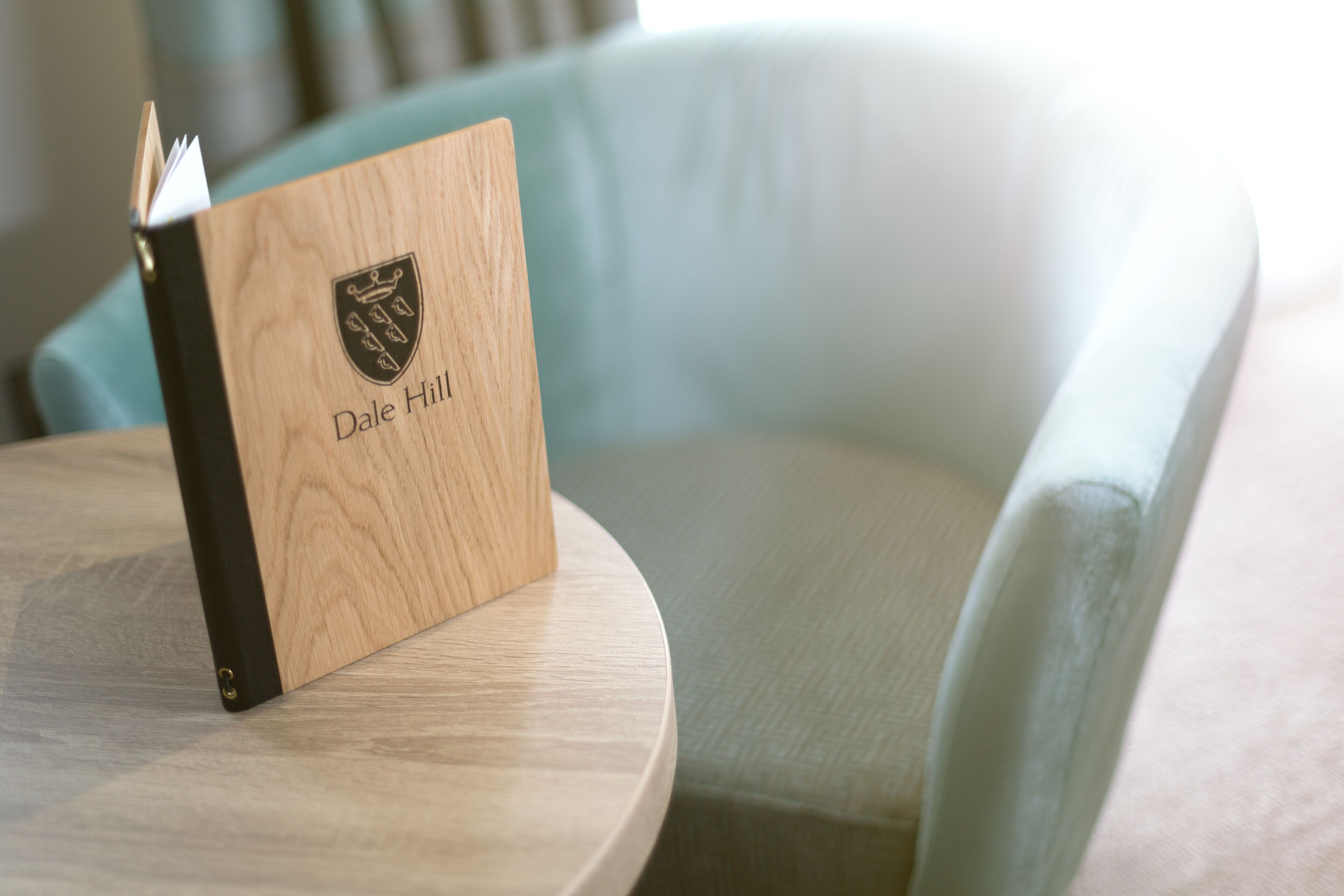 Un libro de madera con el nombre "Dale Hill" grabado, sobre una mesa redonda.