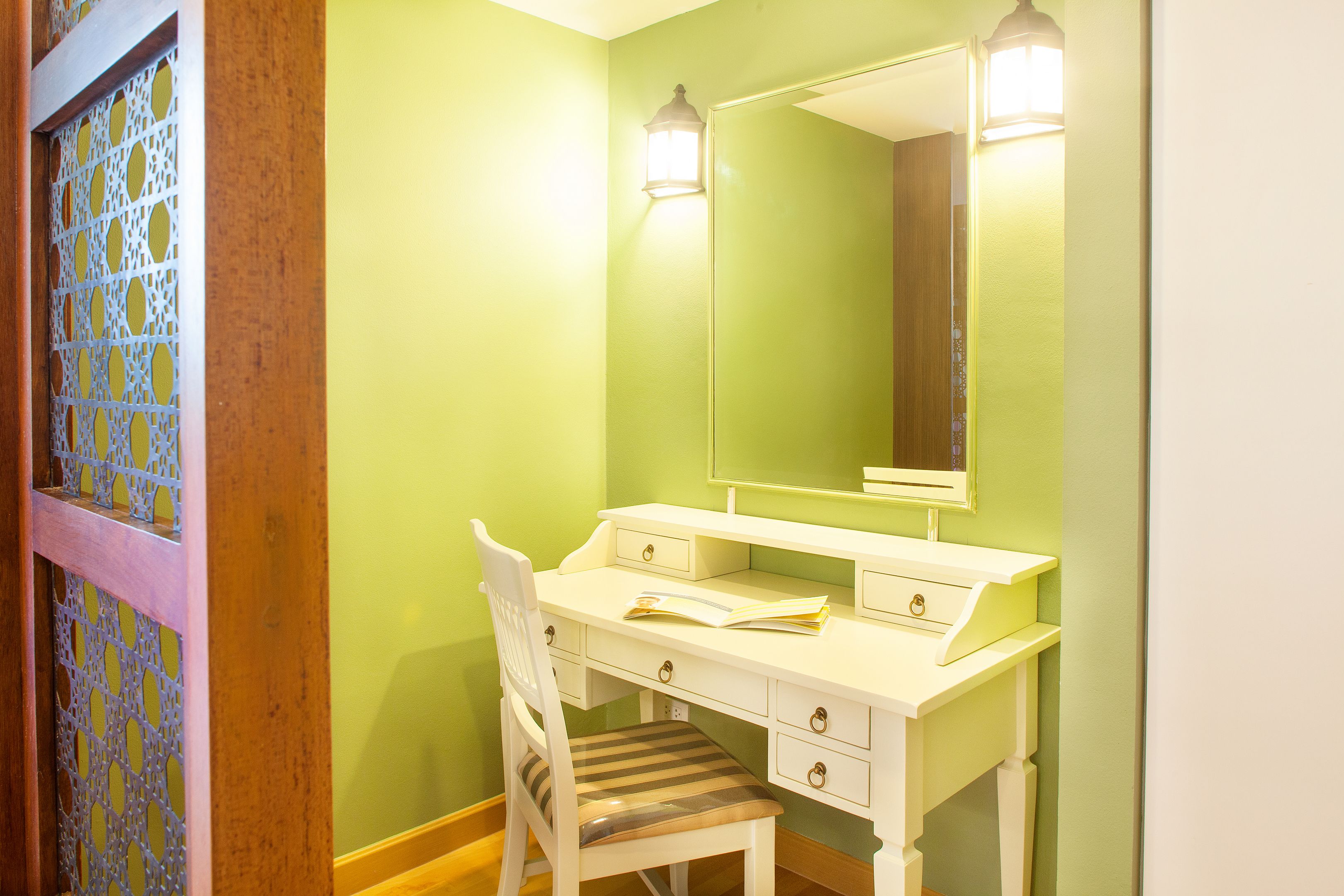 A room with a white desk, a chair, and a mirror.