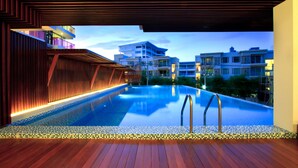 A modern pool area with a wooden deck and a view of surrounding buildings. - Rocco Hua Hin Beach Seaview (Hua Hin)