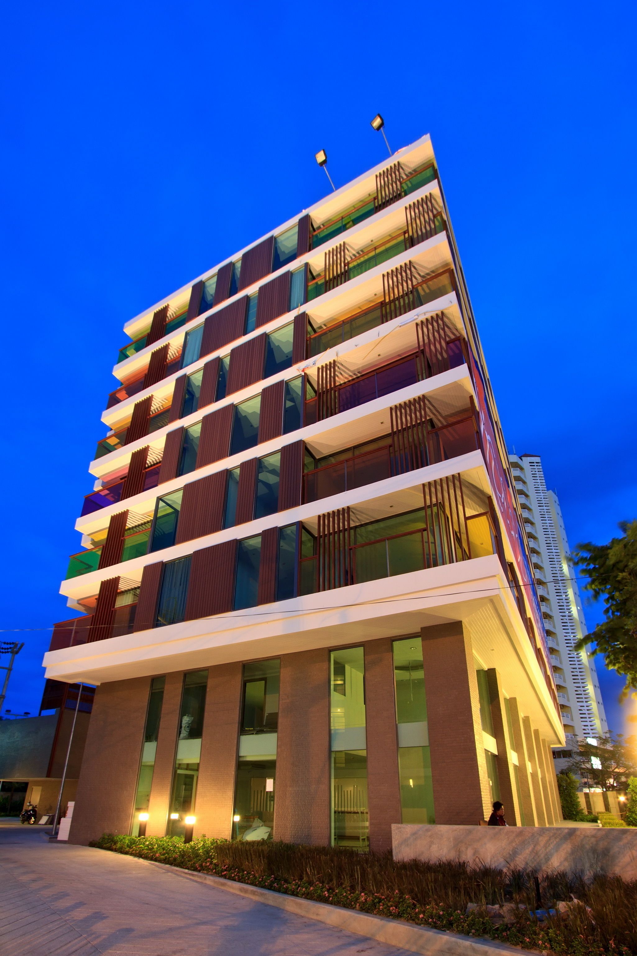 A multi-story hotel with a modern design, featuring balconies on each floor and large windows.