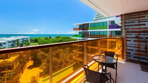 A balcony with a view of the sea, a dining area with chairs, and a building with multiple balconies. - Rocco Hua Hin Beach Seaview (Hua Hin)