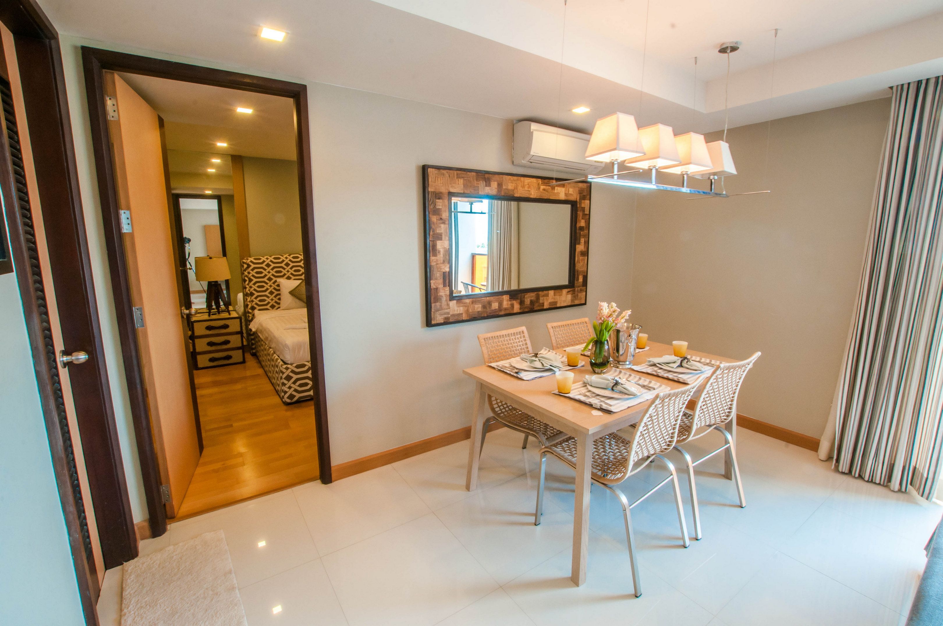 A dining area with a wooden table, white chairs, and a large mirror on the wall.