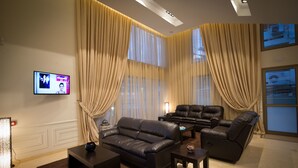Una sala de estar moderna con un sofá, dos sillones, una mesa de centro y un televisor montado en la pared.