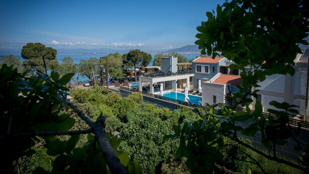 Un resort con piscina, vistas al mar y montañas al fondo.