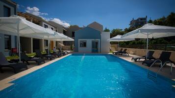 Relax by the pool surrounded by lounge chairs and umbrellas, with modern buildings offering a view of the surrounding landscape.