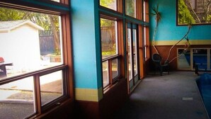 A room with large windows, a blue wall, and a chair. - Kings Motor Inn (Kamloops)