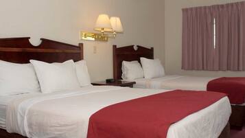 Two double beds with wooden headboards, white bedding, and red throw blankets.