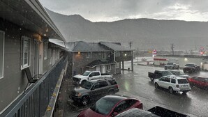 A building with a balcony overlooking a parking area with several cars. - Kings Motor Inn (Kamloops)