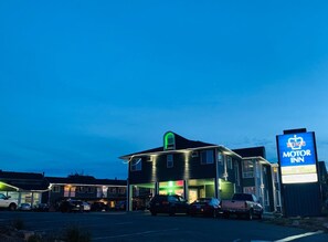 A motel with a large sign, multiple parking spaces, and a well-lit building facade.