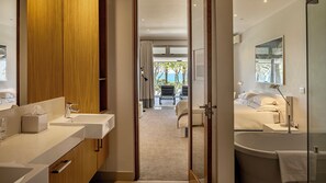 A modern hotel bathroom with dual sinks, a large mirror, and a bathtub.