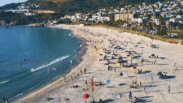 A beach with a mountain in the background, a sandy shore, and buildings along the coastline. - Blue Views Penthouse Beachfront Apartments (Cape Town)