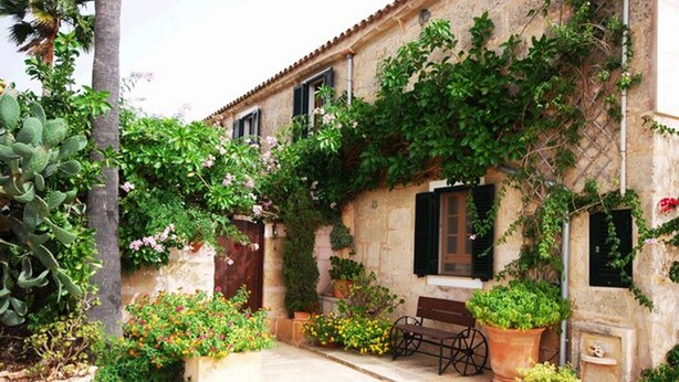 A stone building with a rustic exterior, a bench, and potted plants. - Fínca Líbertad (Campos)