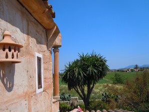 A rustic building with a terracotta facade, a window, and a large tree in the foreground. - Fínca Líbertad (Campos)