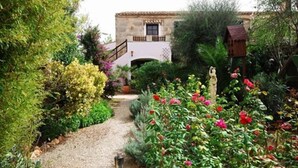 A garden pathway leading to a rustic building with a stone facade and a small archway. - Fínca Líbertad (Campos)
