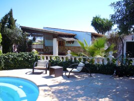 Una piscina al aire libre, sombrillas, sillones reclinables de piscina