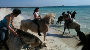 A beach with people riding horses along the shoreline. - Fínca Líbertad (Campos)
