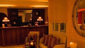 A cozy lobby with a sofa, chairs, a coffee table, and a reception desk. - Damia Hotel (Corfu)