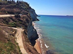A coastal road with a cliffside and beach. - Damia Hotel (Corfu)