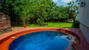 A swimming pool with a brick border, surrounded by a grassy area and trees. - Hotel Boutique Hacienda del Gobernador (Colima)