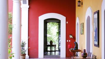 A covered outdoor area with a red wall, white columns, and a table with chairs.