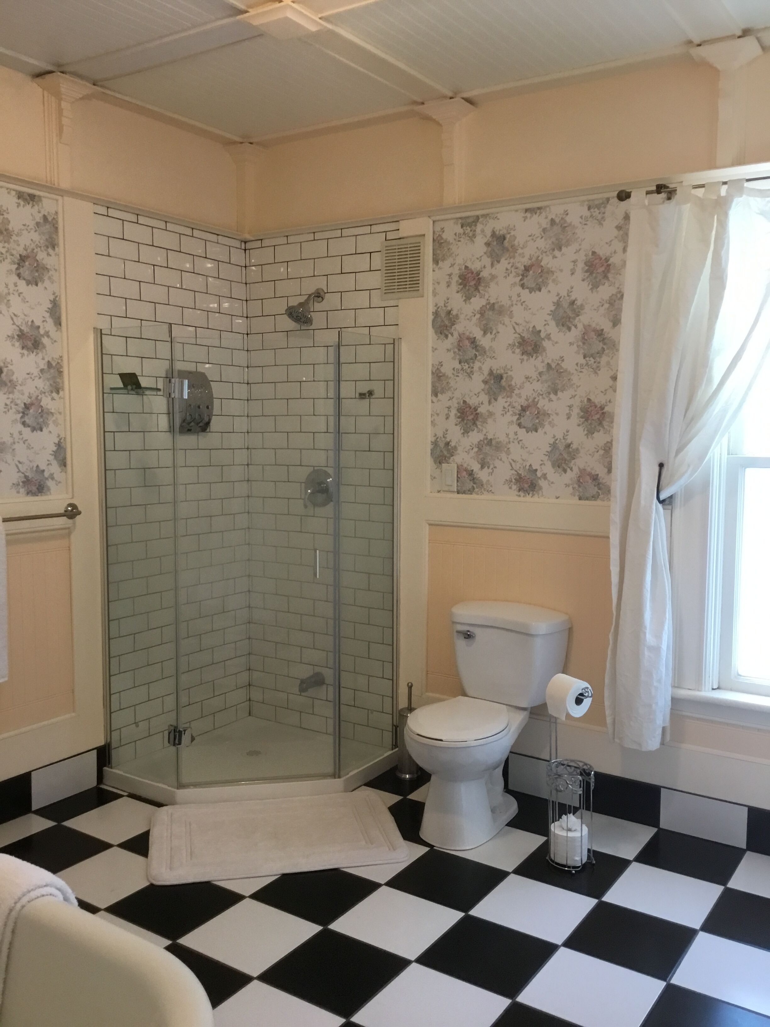 Ein Badezimmer mit Duschkabine, Toilette und einem Schachbrettmuster-Boden.