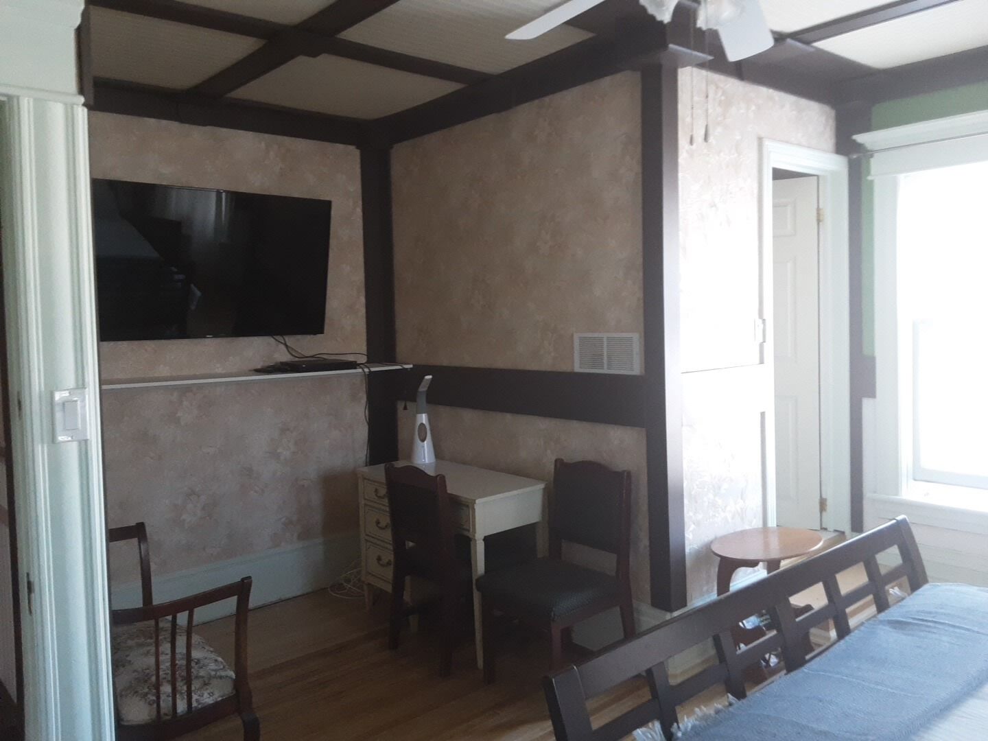 Una stanza con un letto, una scrivania e una sedia. C'è un televisore fissato al muro.