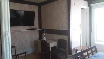 Una stanza con un letto, una scrivania e una sedia. C'è un televisore fissato al muro.