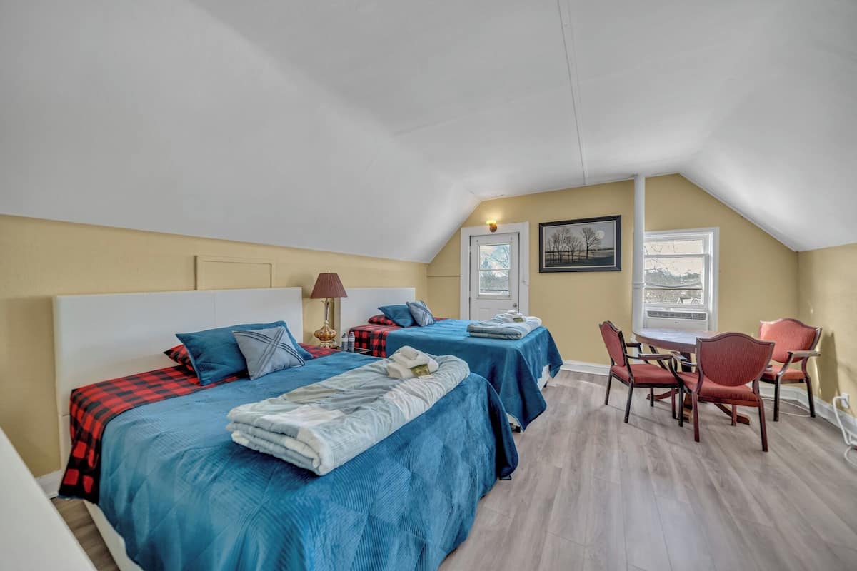 Une chambre avec deux lits, une table à manger avec des chaises et une fenêtre.