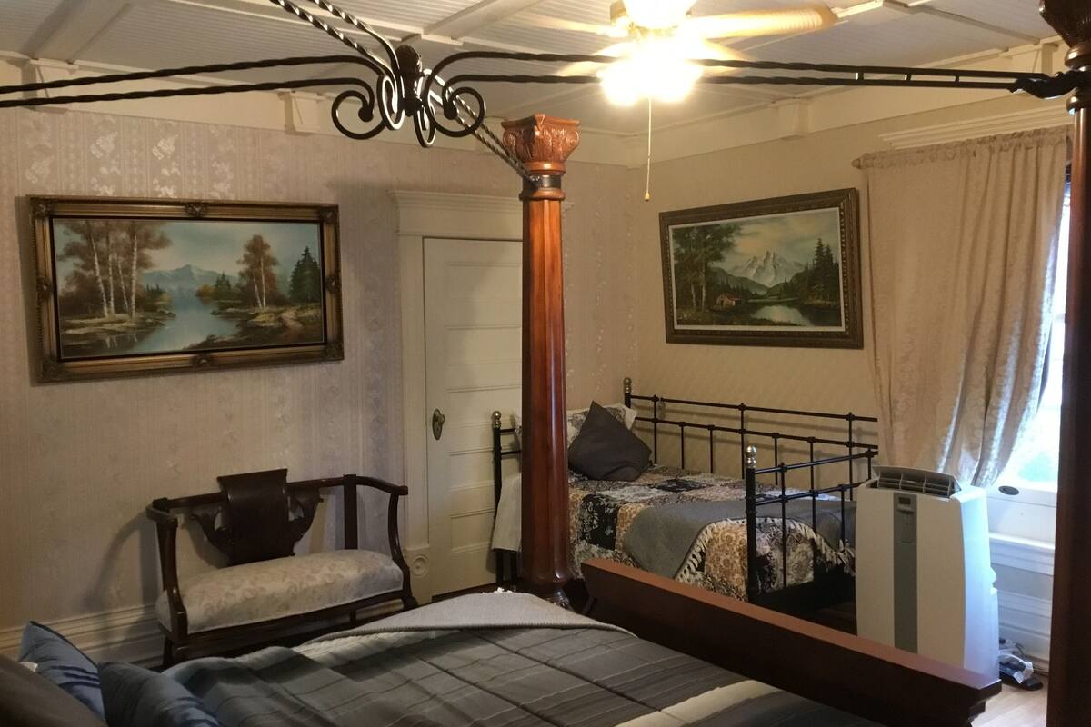 Une chambre à coucher comprenant un lit, une chaise, un bureau, une armoire et deux tableaux accrochés aux murs.
