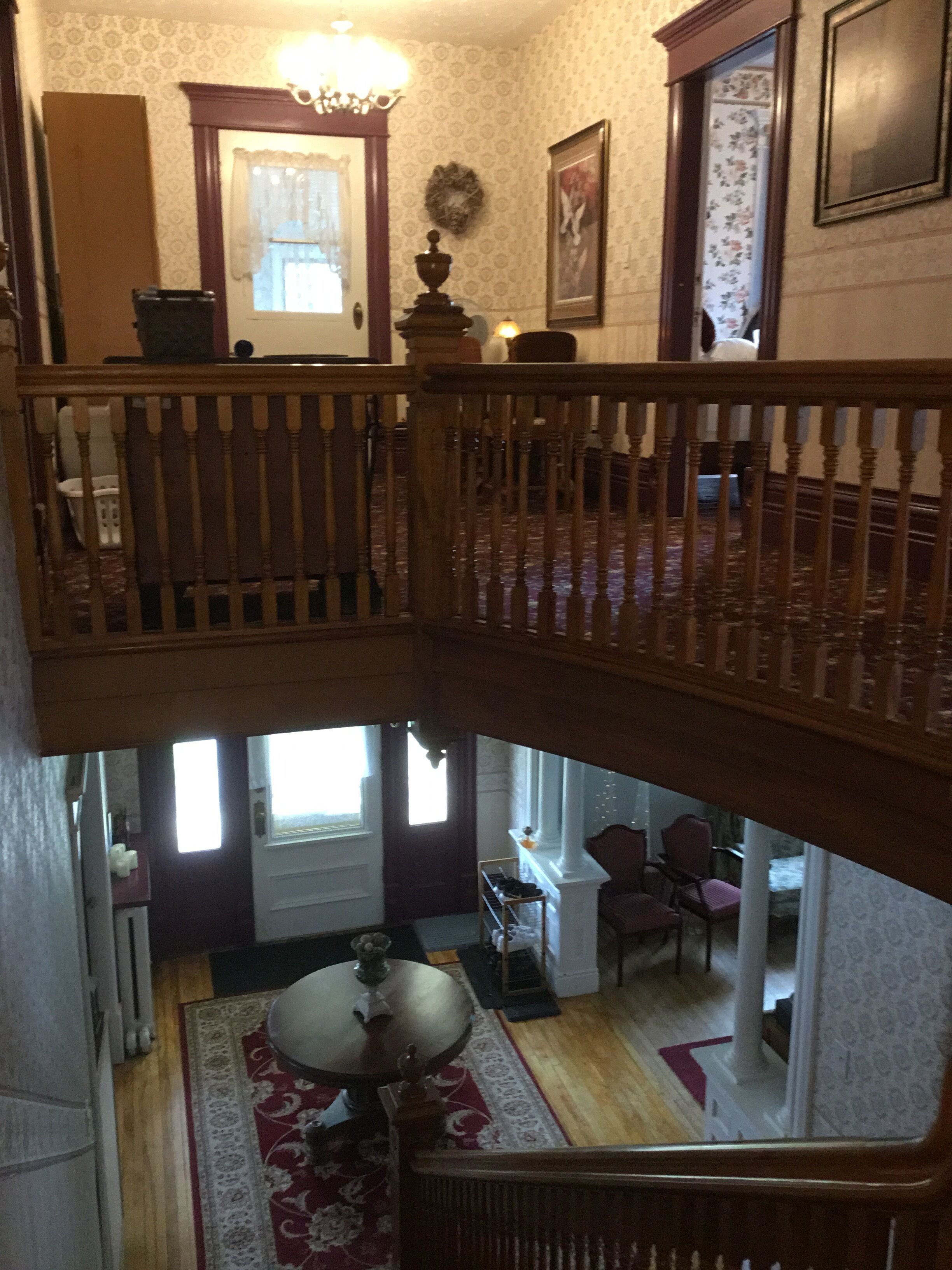A multi-level interior with a staircase, a chandelier, and a dining area with a table and chairs.