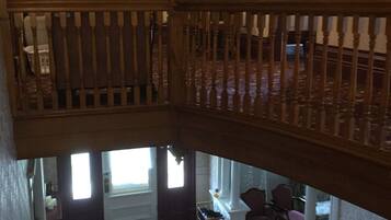 A multi-level interior with a staircase, a chandelier, and a dining area with a table and chairs.