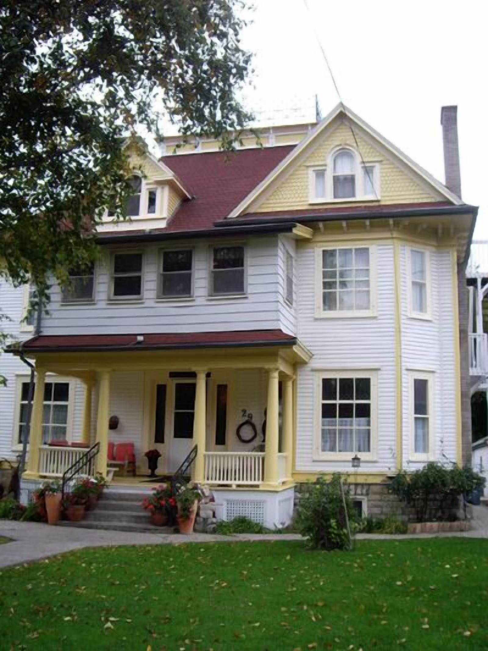 A two-story house with a porch, a small garden, and a mailbox.