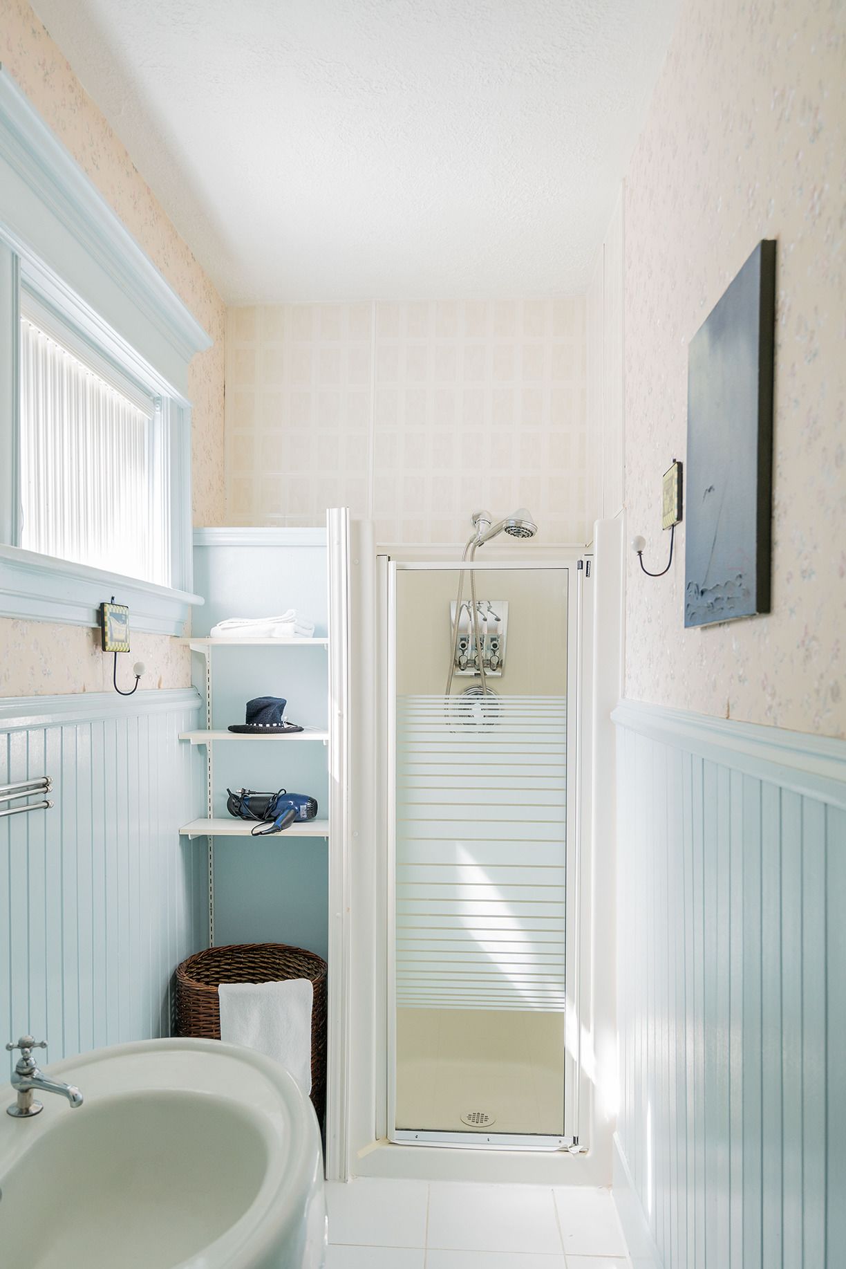 A bathroom with a bathtub, a shower, and a sink. There are shelves with towels and a basket.