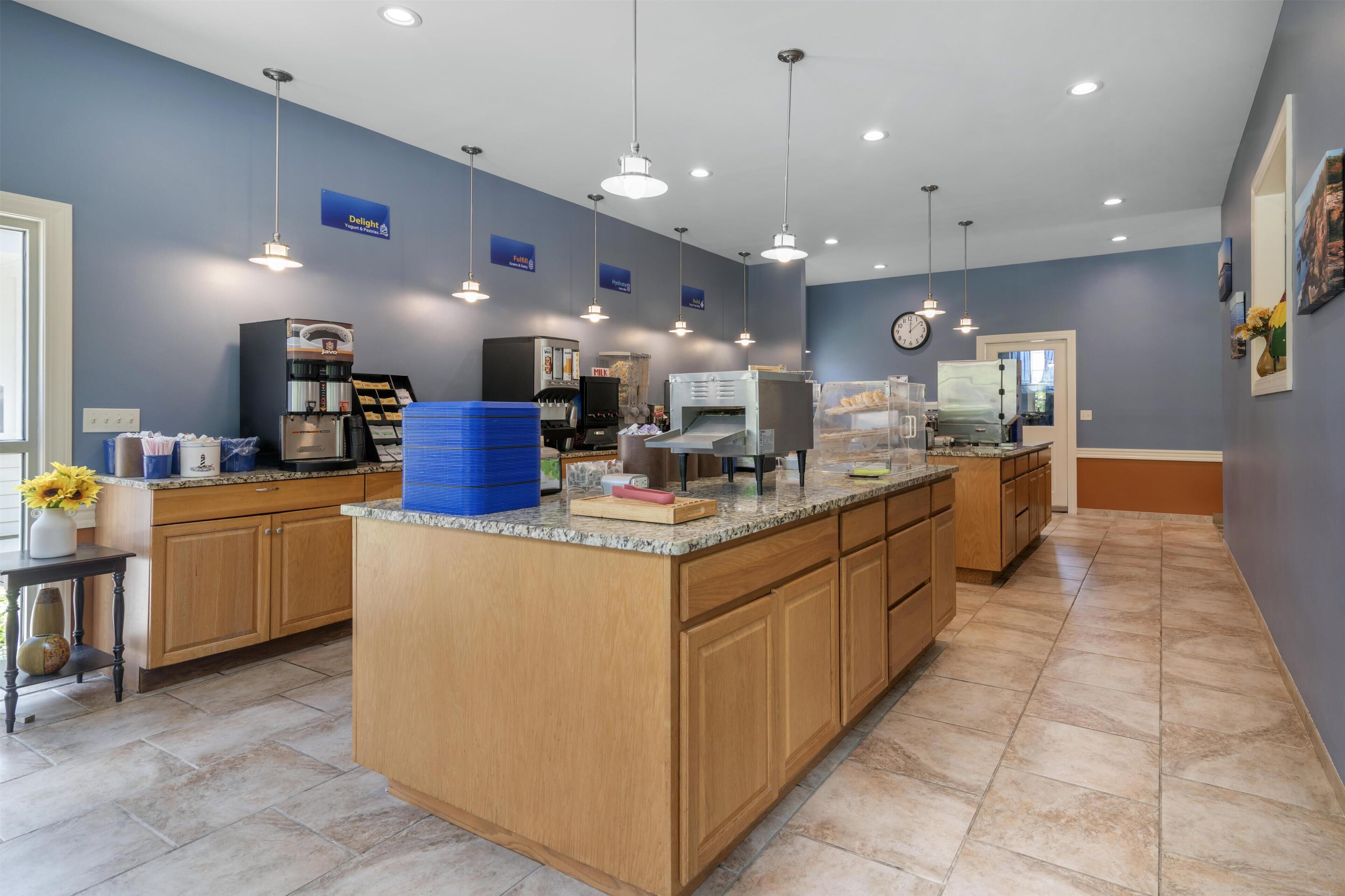 Una cucina moderna con isola centrale, elettrodomestici integrati e illuminazione a sospensione.