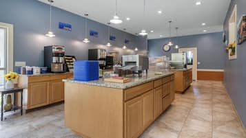 Una cucina moderna con isola centrale, elettrodomestici integrati e illuminazione a sospensione.