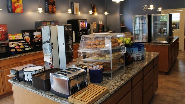 Un comptoir de petit-déjeuner avec divers aliments, une machine à café et un réfrigérateur.