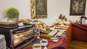 A buffet setup with various food items, a toaster oven, and decorative elements like a small plant and framed artwork.